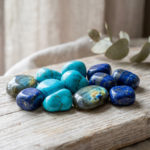Pierre bleue protectrice : l'alliée de votre sérénité 3 Serene arrangement of polished blue protective stones: turquoise, lapis lazuli, and iridescent labradorite on weathered wood.